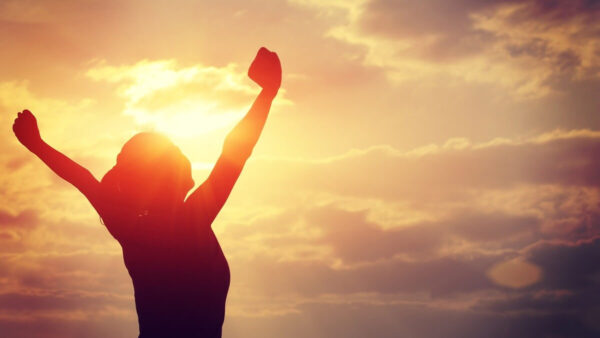 Silhouette of a woman raising their arms at sunrise, symbolizing energy, renewal, and a fresh start to better health.
